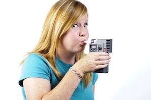 Young redheaded woman blowing into a handheld breathalyzer machine