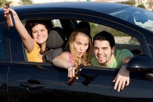 Happy teenagers drinking beer in a car