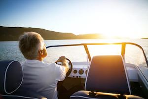 Older man driving a boat.